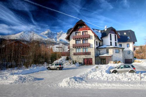 a large building with two cars parked in the snow at Matrix in Tatranská Lomnica