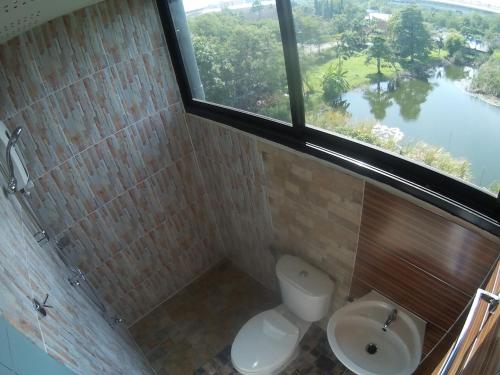 a bathroom with a toilet and a sink and a window at Na Siri Lake View in Samut Prakan