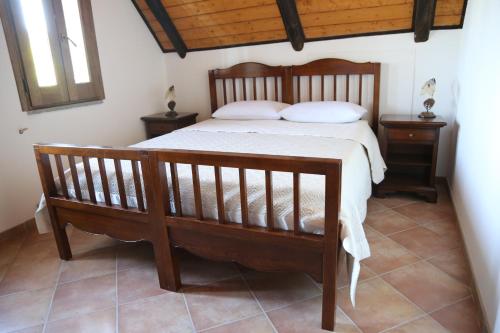 a bedroom with a wooden bed and two night stands at Agriturismo Pirara in Gerocarne