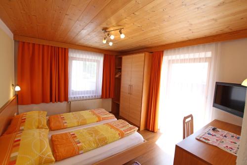 a bedroom with two beds and a television in it at Gästeheim Anni Winkler in Nauders
