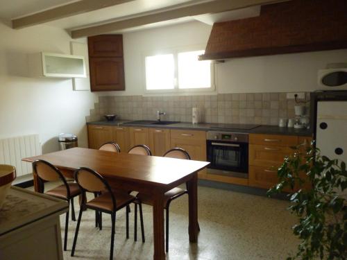 une cuisine avec une table et des chaises en bois dans l'établissement Le Côte d'Albâtre, à Tourville-la-Chapelle