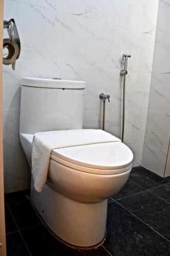 a white toilet in a bathroom with a towel on it at Iconic Suites & Pods Hotel in Ipoh