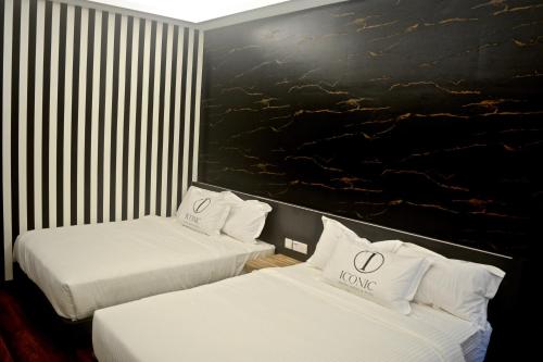 two beds in a hotel room with white sheets at Iconic Suites & Pods Hotel in Ipoh