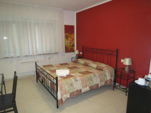 a bedroom with a bed and a red wall at Artisti Rooms in Ravenna