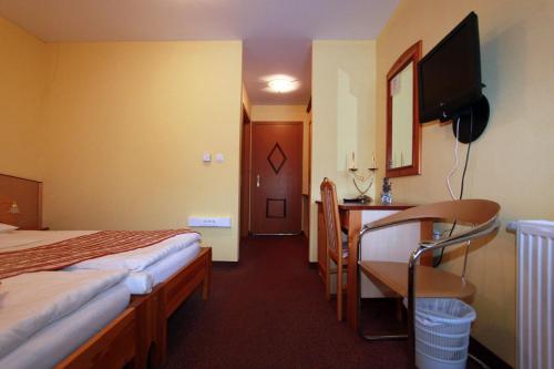 Habitación de hotel con 2 camas, escritorio y TV. en Guesthouse Jurcek en Zreče