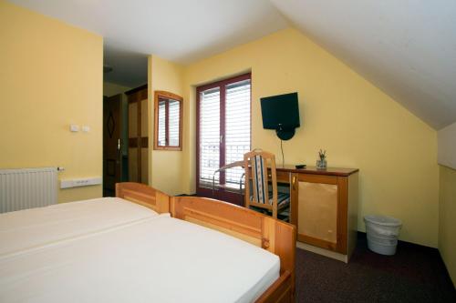 Schlafzimmer mit einem Bett, einem Schreibtisch und einem TV in der Unterkunft Guesthouse Jurcek in Zreče