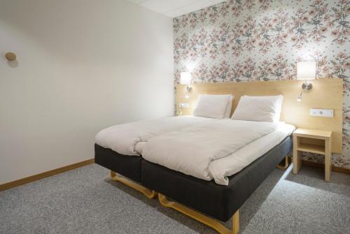 a bedroom with a large bed with a floral wallpaper at First Hotel Dragonen in Umeå
