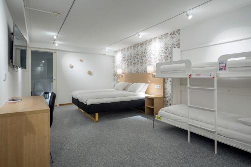 a room with two bunk beds and a desk and a bed at First Hotel Dragonen in Umeå