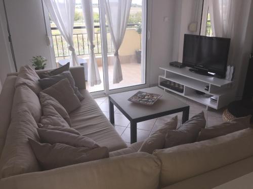 a living room with a couch and a tv at POSSIDI - Ithaki Holiday Apartments in Kalandra
