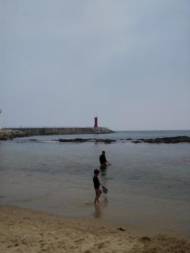 a man and a child playing in the water on the beach at Sun Motel in Gangneung