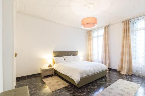 - une chambre blanche avec un lit et une lampe dans l'établissement Appartement du Thiers, à Nice