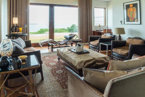 a living room with couches and chairs and a large window at Schulphoek Seafront House in Hermanus