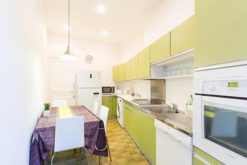 eine Küche mit grünen und weißen Schränken und einem Tisch in der Unterkunft Appartement du Thiers in Nizza