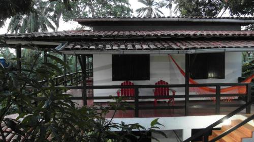 two red chairs sitting on the porch of a house at Pousada Casa da Edinha in Ilha de Boipeba