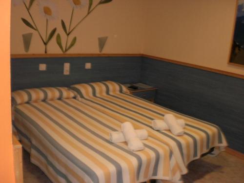 1 dormitorio con 1 cama de rayas y 2 almohadas blancas en Hostal El Cartero en Teruel