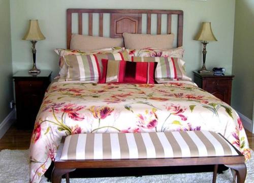 1 dormitorio con 1 cama grande con flores rosas en Gooromon Park Cottages, Canberra, en Hall