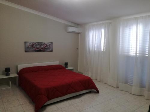 1 dormitorio con cama roja y cortinas blancas en XXI Agosto Home, en Reggio Calabria