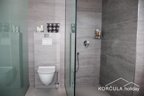 a bathroom with a toilet and a glass shower at Korcula Holiday in Korčula