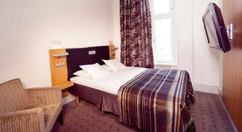 a bedroom with a bed and a tv and a window at Home Hotel Bilan in Karlstad