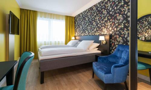 a bedroom with a bed and a blue chair at Thon Hotel Triaden in Lorenskog