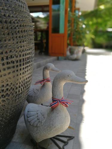 a group of three ducks sitting next to a vase at Bann Vimansamutr in Cha Am