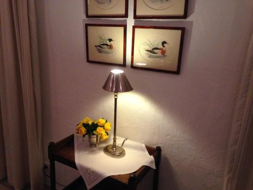 a table with a lamp and a vase of flowers on it at Waldhaus an de Miälkwellen in Ladbergen