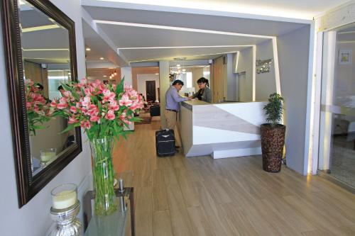a lobby with a counter with pink flowers in a vase at Samana Hotel in Arequipa