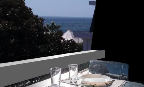 a table with a plate and glasses on a balcony at Cascais-Estoril BEACHFRONT Apartments in Estoril