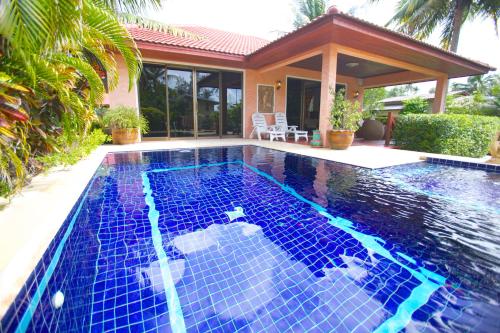 a swimming pool in front of a house at Sunshine Residence in Baan Tai