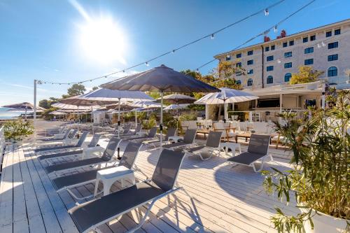a group of chairs and umbrellas on a deck at Hotel Brown Beach House & Spa in Trogir