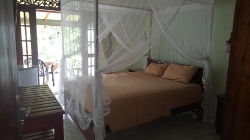 a bedroom with a white bed with a canopy at Mahi Villa in Bentota