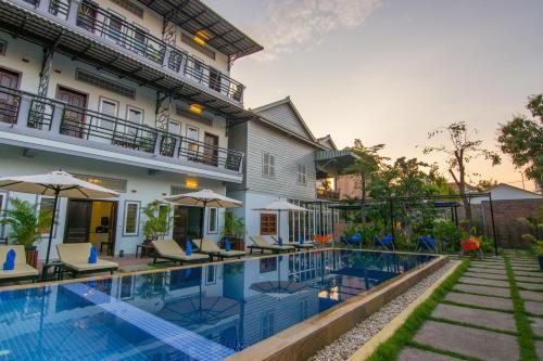 a hotel with a swimming pool in front of a building at The Local Time Village in Siem Reap