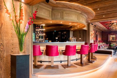 a bar with red stools in a restaurant at Alpin Resort Sacher in Seefeld in Tirol