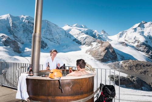 a couple of people in a hot tub in the mountains at Berghaus Diavolezza in Berninahäuser
