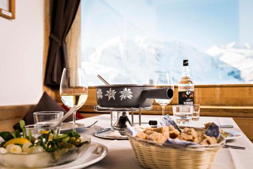 a table with glasses of wine and a basket of food at Berghaus Diavolezza in Berninahäuser