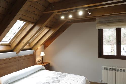 Casa Bielsa في بييلسا: غرفة نوم بسقوف خشبية وسرير ونوافذ