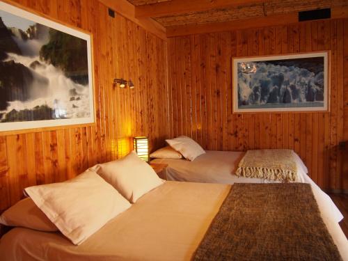 two beds in a room with wood paneling at Hotel Último Paraíso in Cochrane