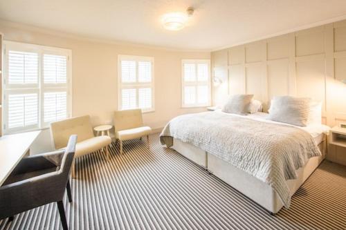 a bedroom with a bed and a desk and chairs at Les Douvres Hotel in St Martin Guernsey