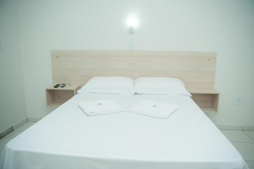a white bed in a room with a headboard at Pousada Pouso Ideal in São Salvador