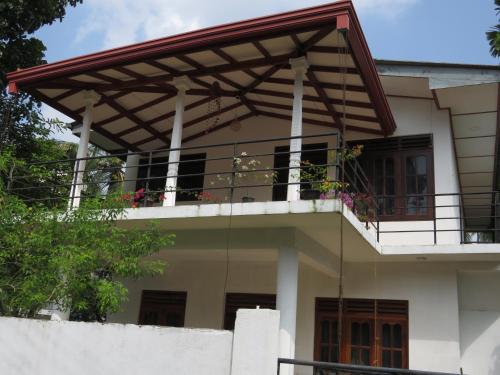 a house with a balcony with flowers on it at Villa Ok in Unawatuna