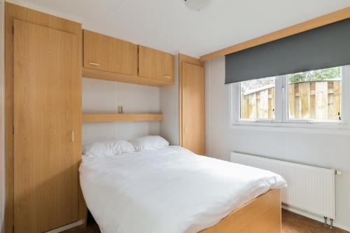 a bedroom with a large white bed and a window at De Bijsselse Enk, Keizerskroon in Nunspeet