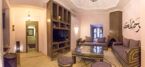 a living room with a couch and a tv at Dar Andamaure in Marrakech