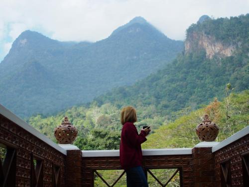 a woman taking a picture of the mountains at Ashi Guesthouse Chiangdao in Chiang Dao