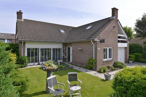 a house with two chairs and a table in the yard at MeerZee in Vrouwenpolder