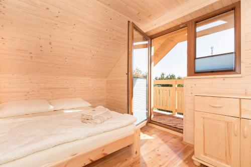 a wooden cabin with a bed in a room with a window at Kameleon2 in Dźwirzyno