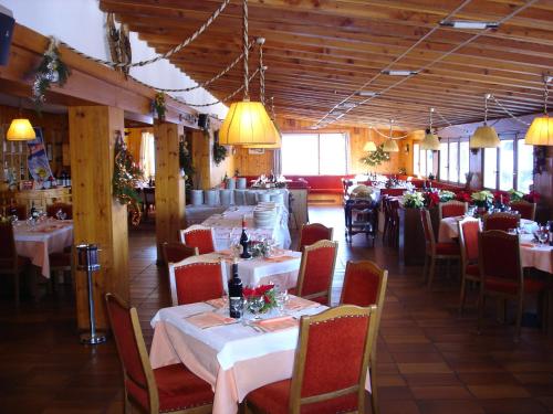 una sala da pranzo con tavoli, sedie e luci di Rifugio Camparient a Scopello