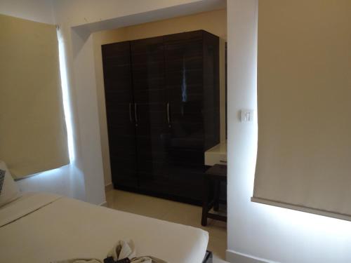 a bedroom with a black cabinet and a white bed at Convastay Gajel- Near Apollo Greams Road in Chennai
