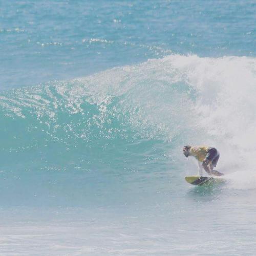 a man riding a wave on a surfboard in the ocean at Plantation Surf Inn & Restaurant - Midigama in Midigama