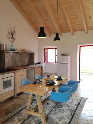 a kitchen with a wooden table and blue chairs at village loft in Cercal