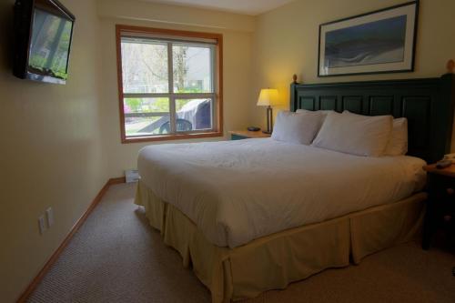 a bedroom with a large bed and a window at Aspens Mountain Side Resort in Whistler
